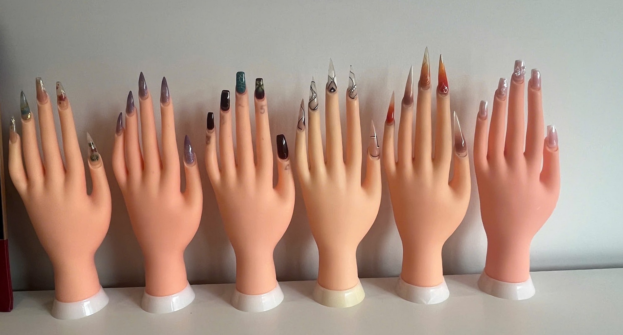 Zes oefenhanden op een plank, elk met een andere set nail art