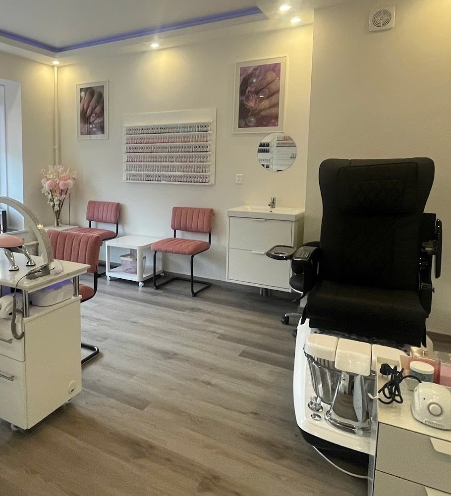 De studio: roze manicurestoelen aan witte tafels, een wand met kleurtips en de zwarte pedicurestoel met massagefunctie