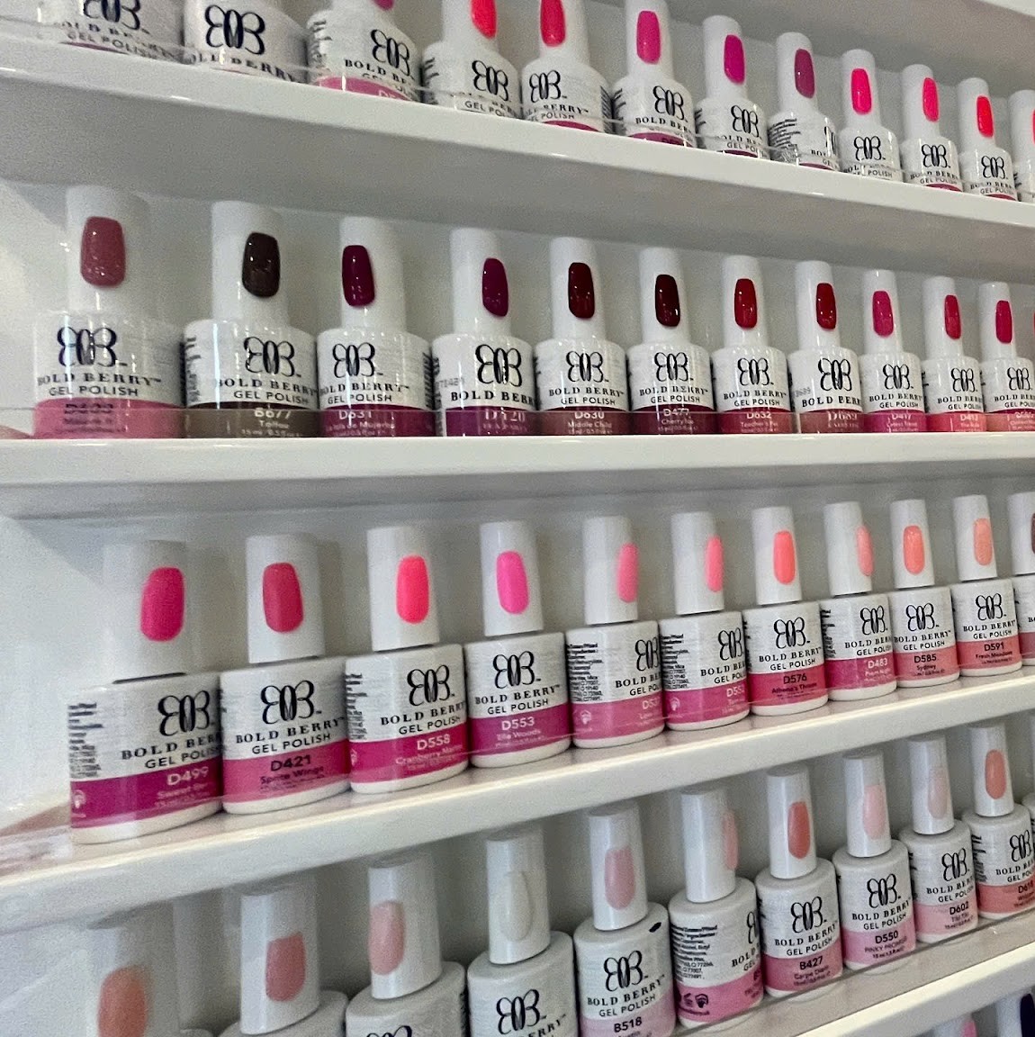 Een wand met rijen flesjes gellak in roze, rood en nude tinten